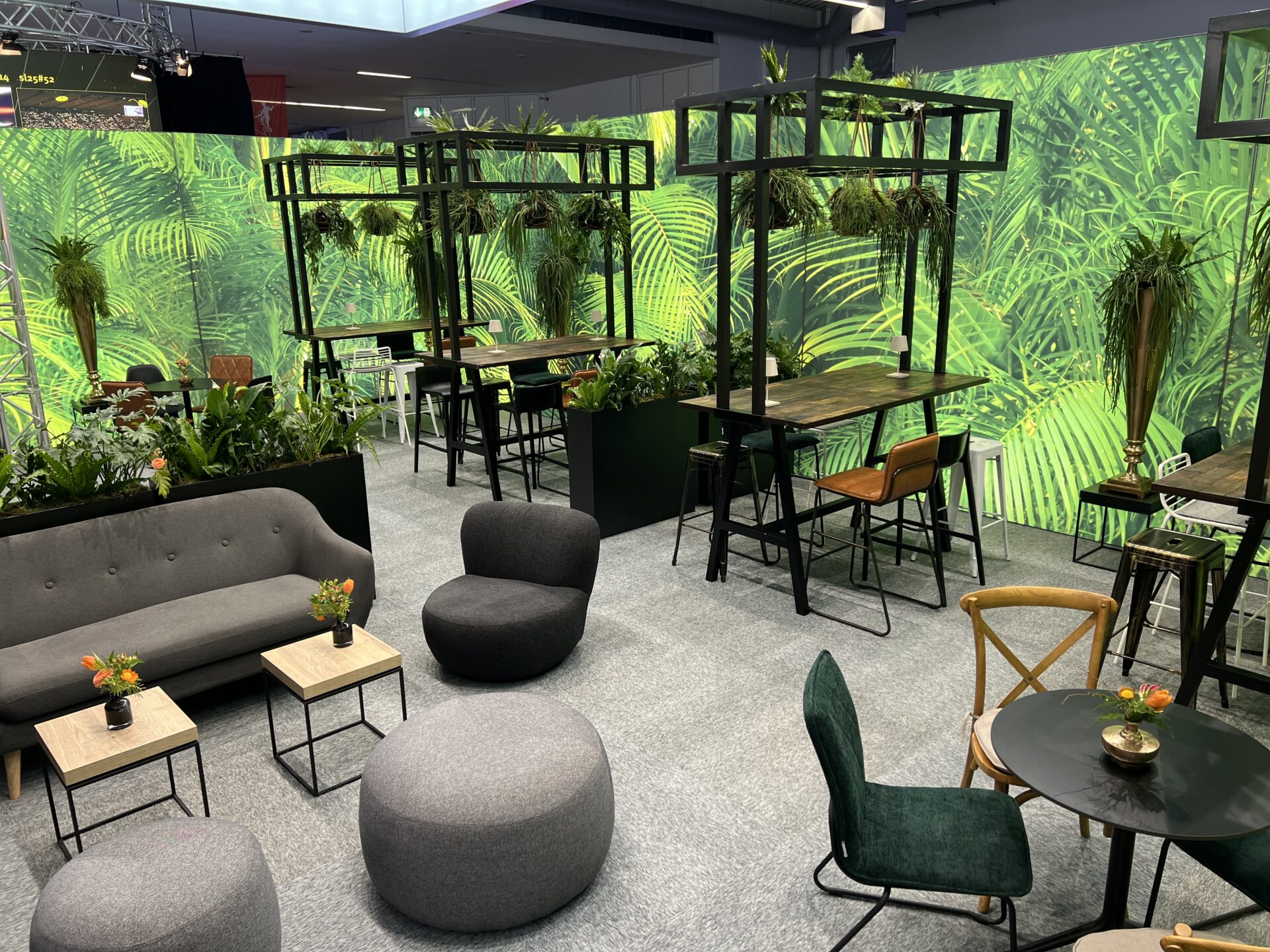 Messestand von Event Rent mit Hightable Comfort, gemischter Bestuhlung und Urban Jungle Wanddeko.